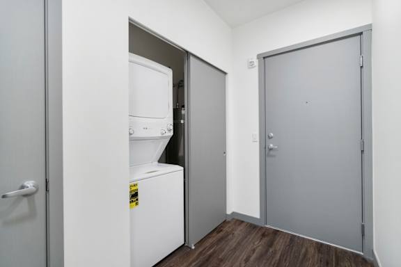 A white refrigerator is in a room with a grey door.