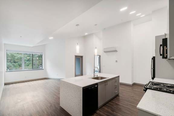 a kitchen and living room with white walls and wood flooring