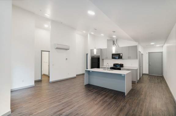 A modern kitchen with a wooden floor and white walls.