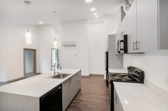 A modern kitchen with a white countertop and black appliances.