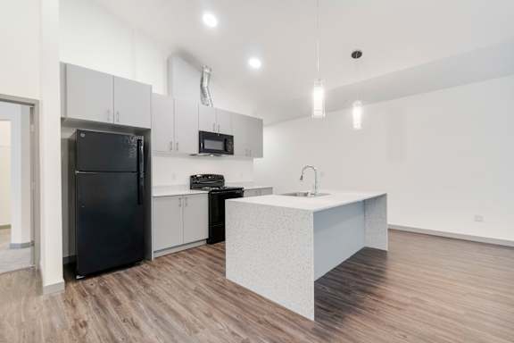 A kitchen with a black fridge and a white counter.