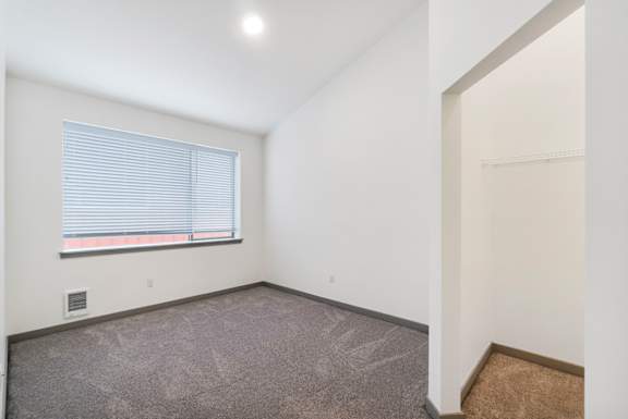 a bedroom with a large window and white walls
