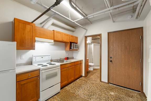 A kitchen with white appliances and wooden cabinets.