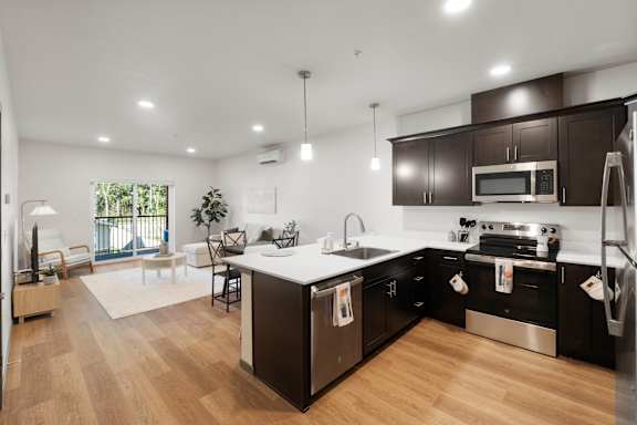 A modern kitchen with dark brown cabinets and stainless steel appliances.
