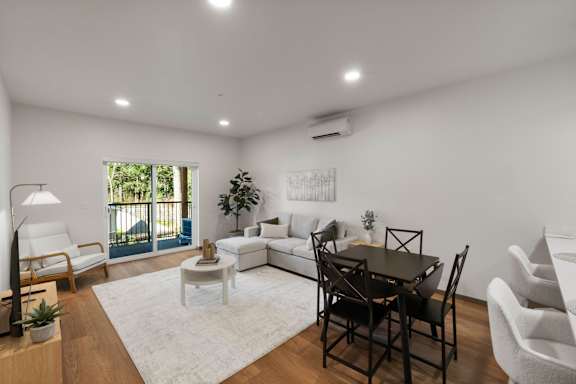 A well-lit living room with a dining table and chairs.
