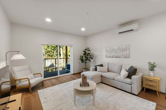 A living room with a white couch, a wooden coffee table, and a large window.