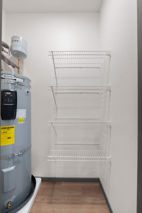 A wall of empty shelves next to a water heater.