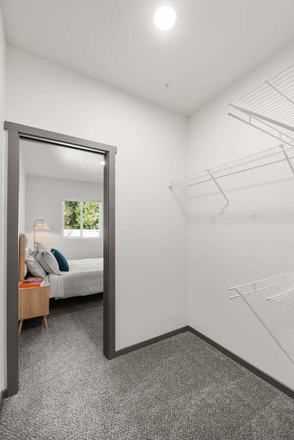 A bedroom with a bed, a mirror, and a shelf.