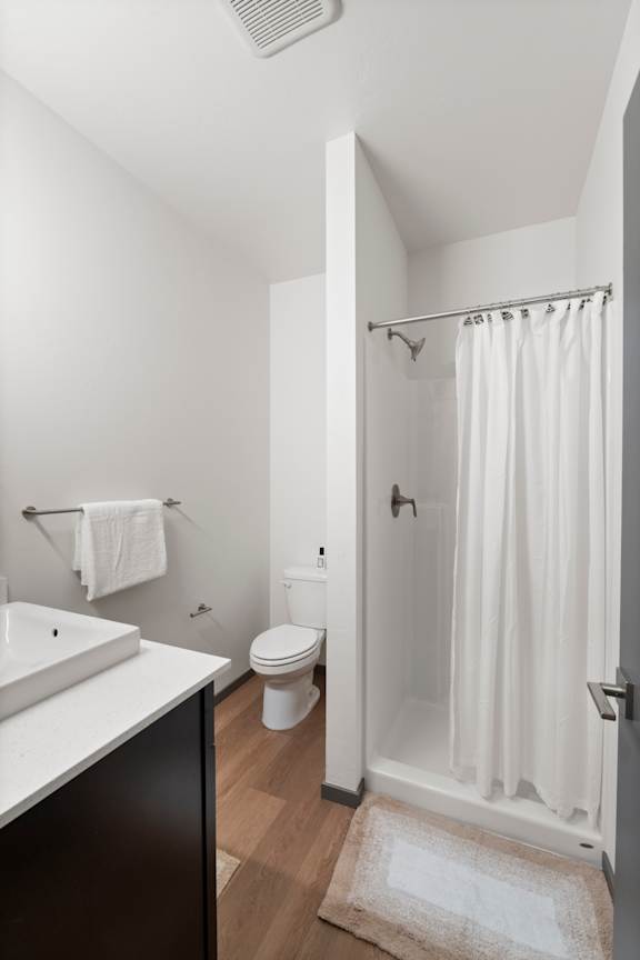 A white bathroom with a toilet, sink, and shower.