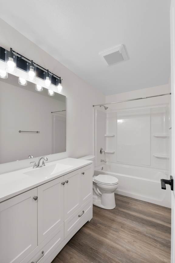 A white bathroom with a sink, toilet, and mirror.