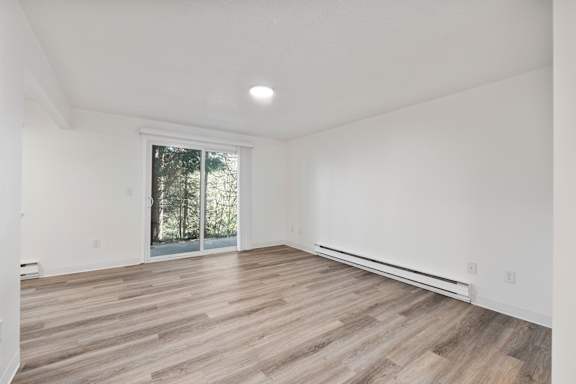 A room with a sliding glass door leading to a wooded area.