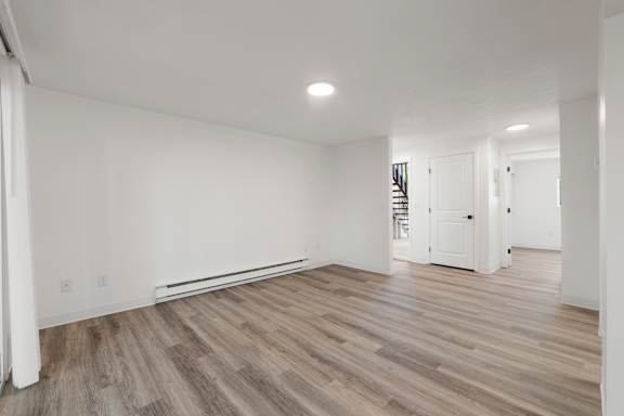 A room with wooden flooring and white walls.