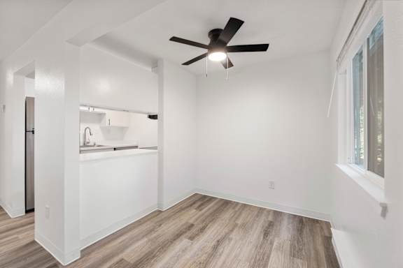 A room with a ceiling fan and wooden flooring.