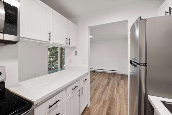 A modern kitchen with white cabinets and a stainless steel refrigerator.