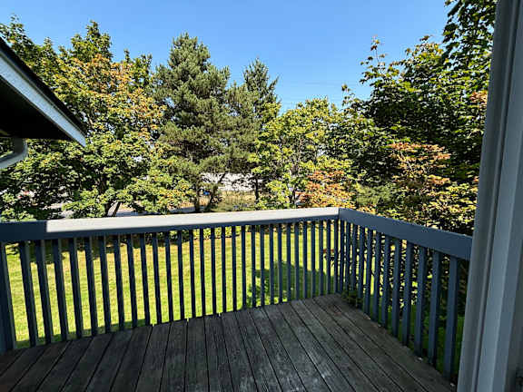 A wooden deck with a railing overlooking a grassy area.