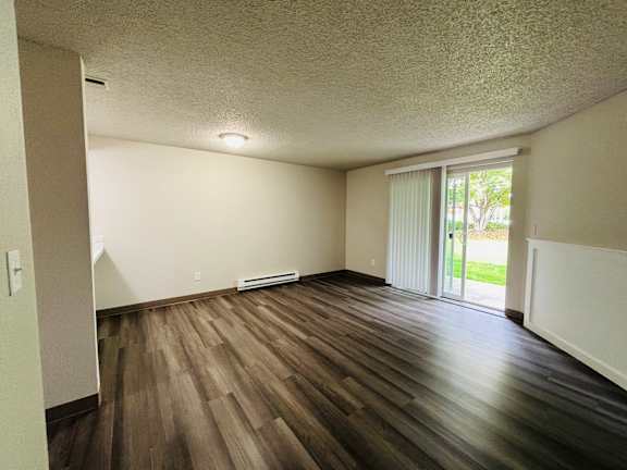A room with wooden flooring and a sliding glass door.