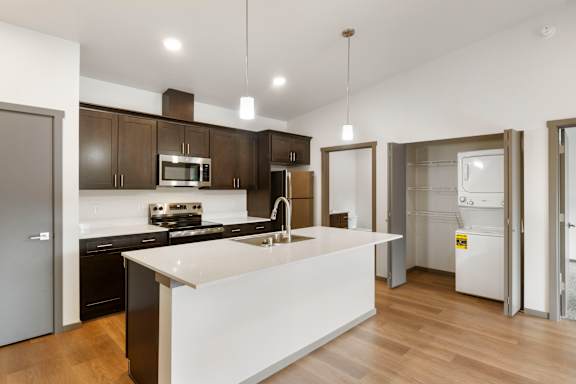 A modern kitchen with a white island and dark brown cabinets.