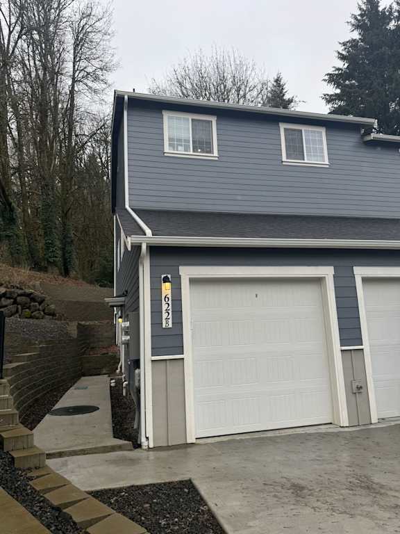 A two-car garage with a grey house in the background.