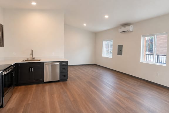 A kitchen with dark wood floors and white walls.