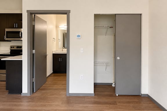 A kitchen with a refrigerator and a pantry with a door open.