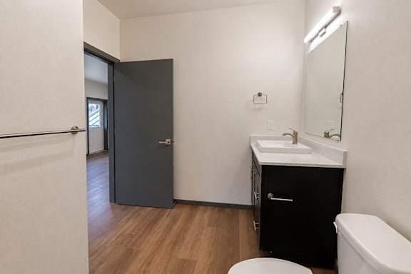 A bathroom with a toilet, sink, and mirror.
