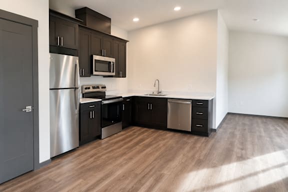 A modern kitchen with dark wood cabinets and stainless steel appliances.
