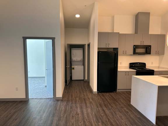 an open kitchen with a black refrigerator freezer next to a black stove top oven