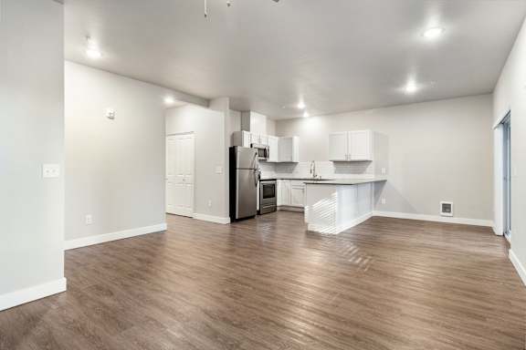 a spacious living room with a kitchen in the background