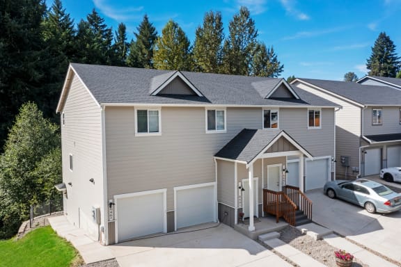a gray house with two garage doors and a driveway