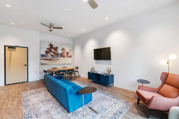 A living room with a blue couch, a brown chair, and a painting on the wall at The Hub Apartments, Washington