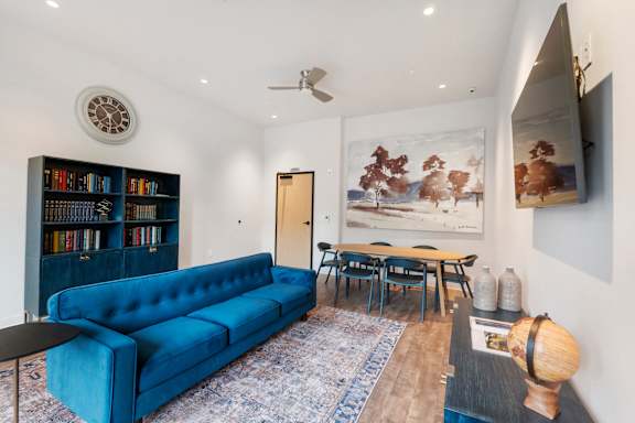 A living room with a blue couch, a bookshelf, and a painting on the wall at The Hub Apartments, Lacey, Washington