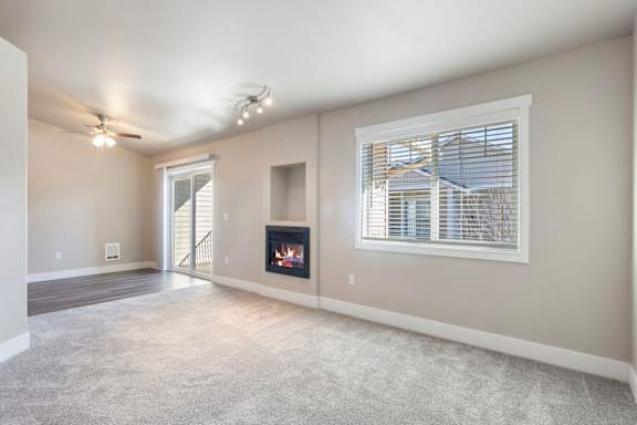 A living room with a fireplace and a ceiling fan.