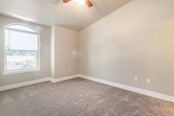 A room with a ceiling fan and a window with blinds.