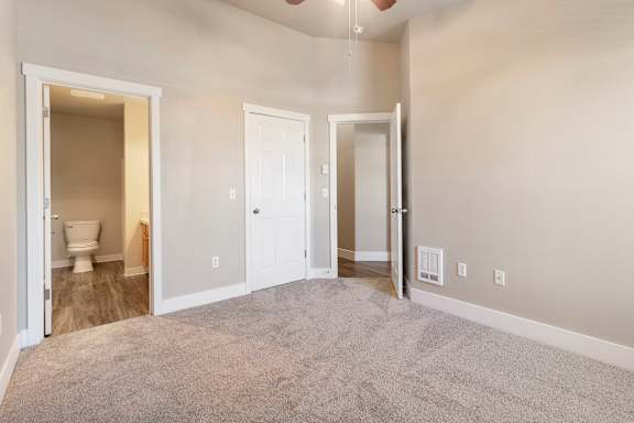 A room with a carpeted floor and three doors.
