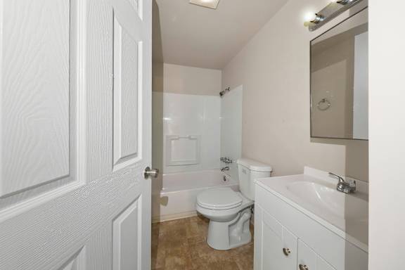 A white bathroom with a toilet, sink, and shower.
