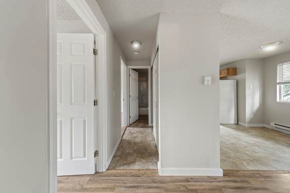 A long hallway with white walls and a rug on the floor.