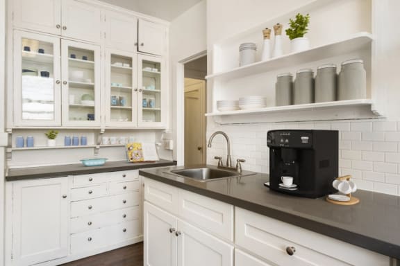 a kitchen with white cabinets and a sink and a coffee maker