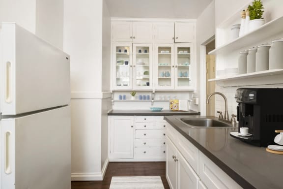 a kitchen with white cabinets and a sink and a refrigerator