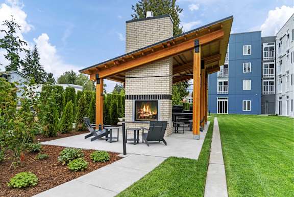 A modern outdoor patio with a fireplace and seating area at The Hub Apartments, Washington 98503