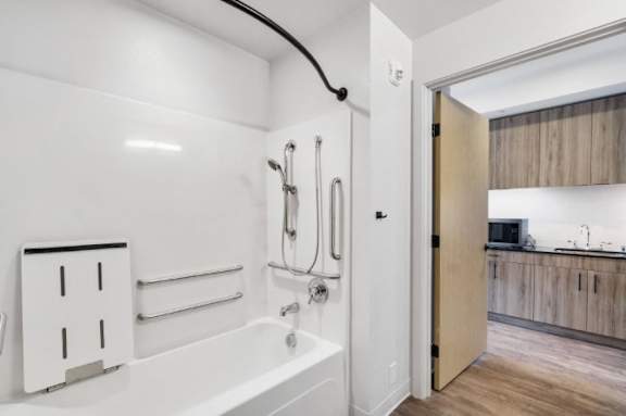 A white bathroom with a tub, shower, and a wooden floor.