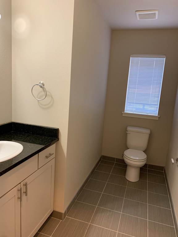 A bathroom with a toilet, sink, and window.