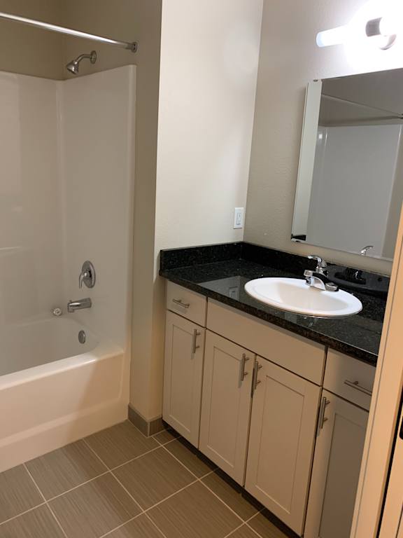 A bathroom with a white tub and a black cabinet above it.