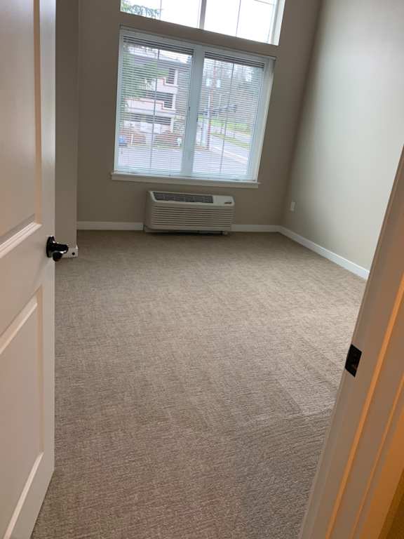 A room with a window, air conditioner, and a wall with a textured surface.