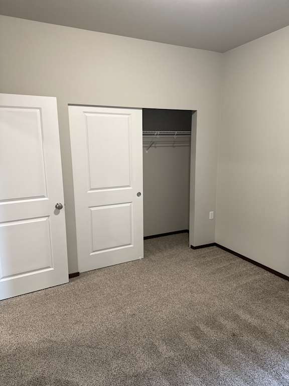 A white door is open to a small room with a carpeted floor.
