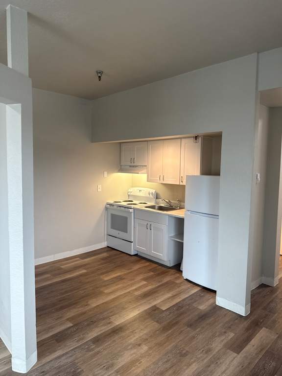 A kitchen with wooden floors and white cabinets.