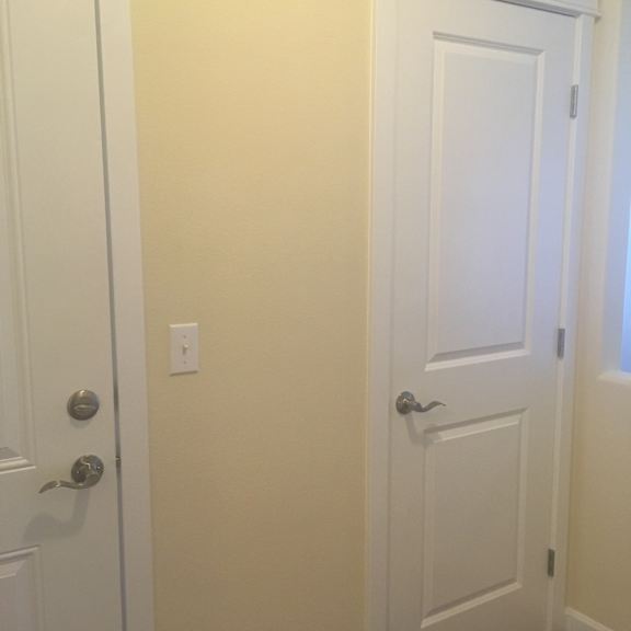 A white door with a silver handle and a light switch on the wall.