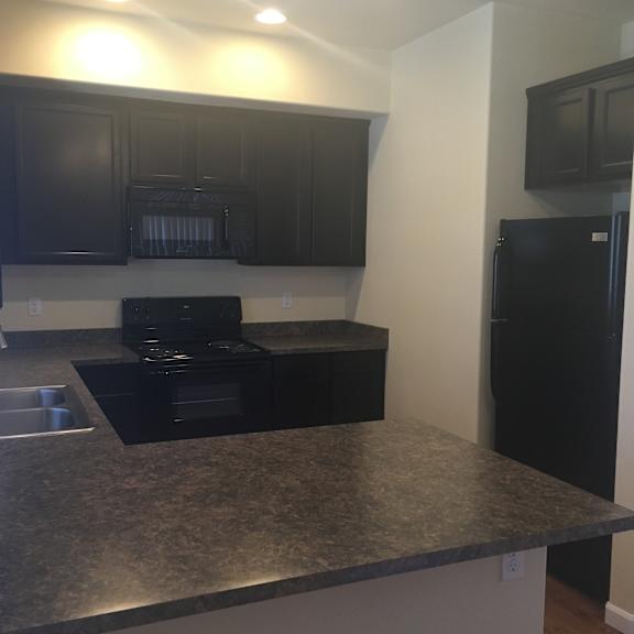 A kitchen with black cabinets and a microwave.