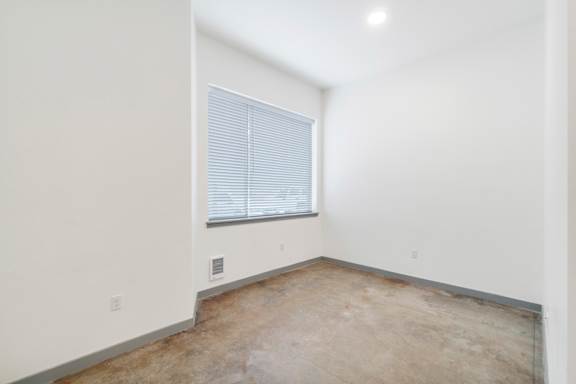 a bedroom with white walls and a window