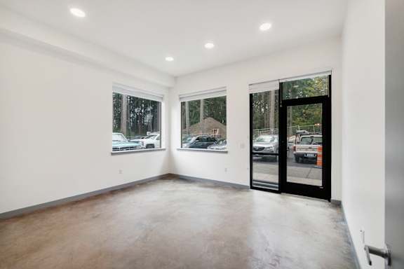 a living room with white walls and a glass door with a view of a parking lot