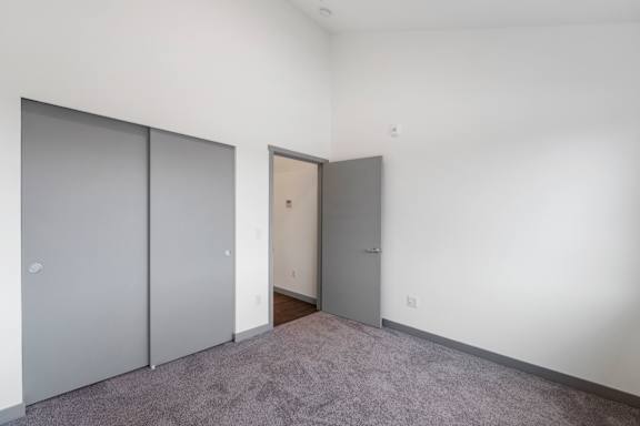 A room with a grey carpet and three doors.